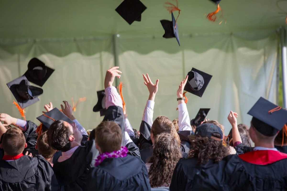 ragazzi diplomati che lanciano il cappello in aria